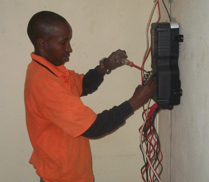 Woco Solar technician performing electrical wiring work at agricultural farm in Dubréka, Guinea - 2018