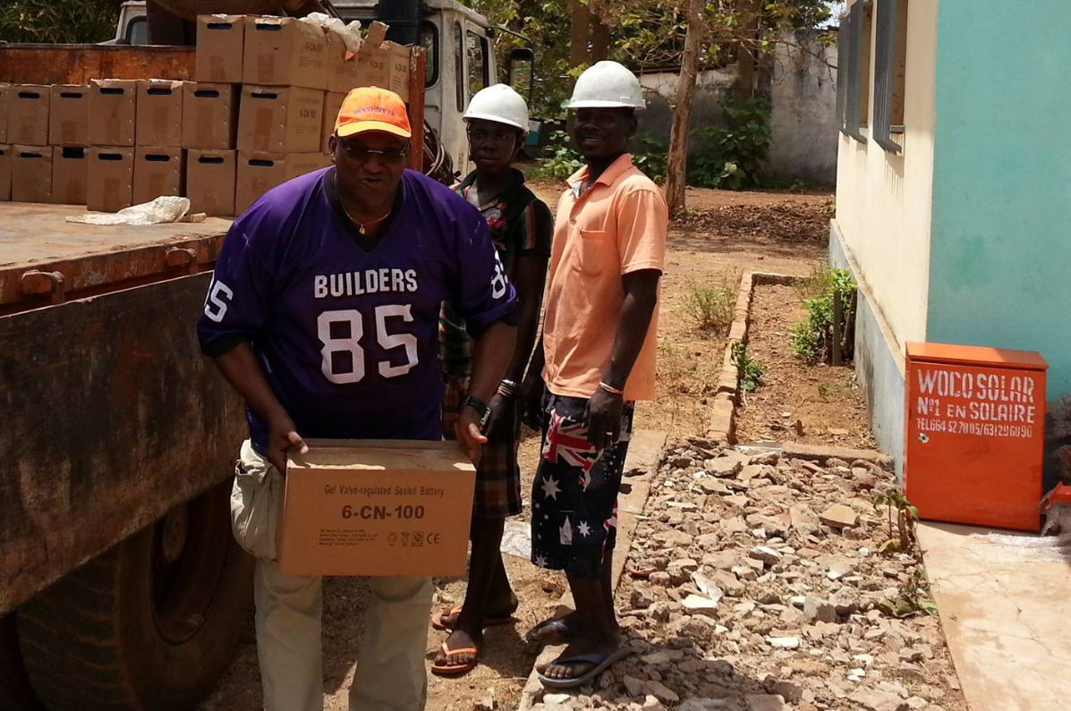 Woco Solar team with solar batteries at health center installation in Mamou, Guinea - 2006