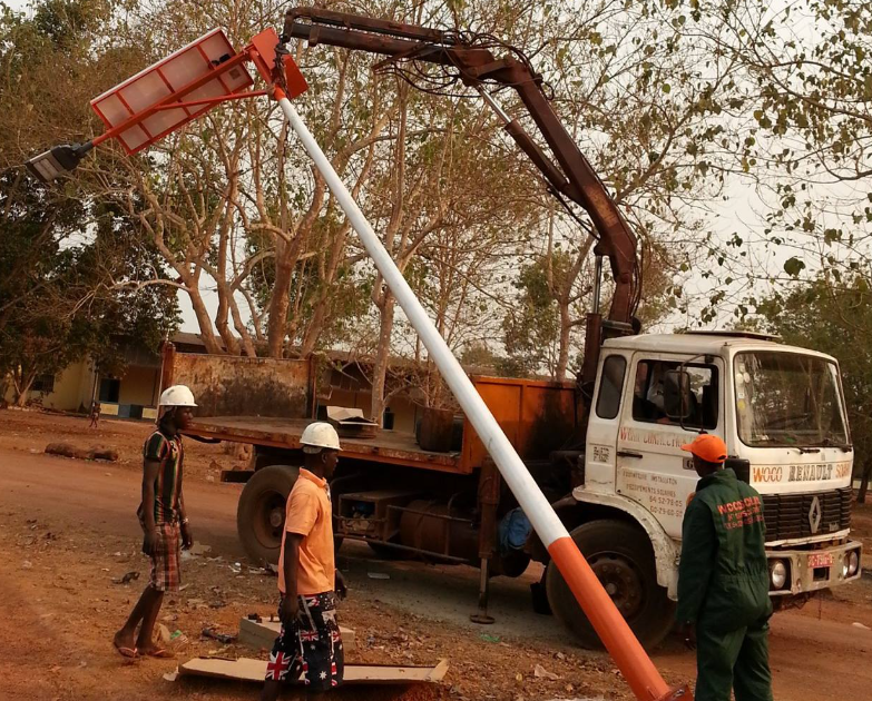 Woco Solar team installing street lighting poles using crane truck in N'Zérékoré, Guinea - 2009